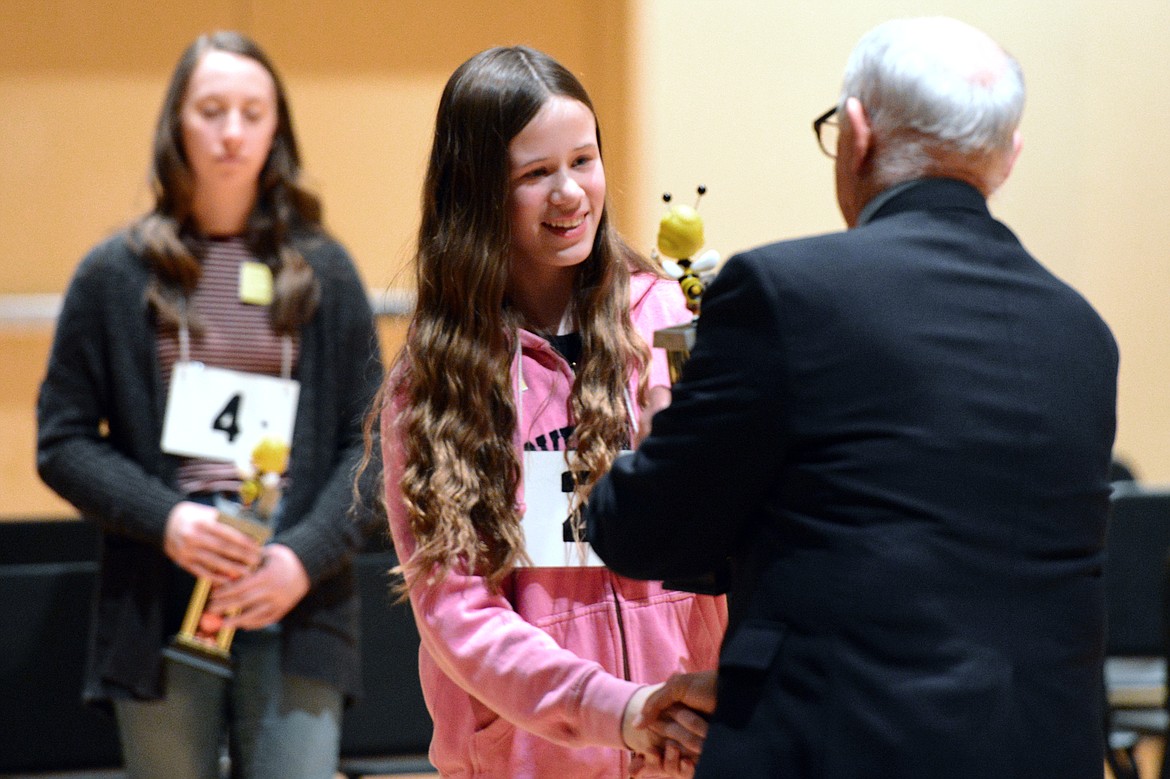 Karrissa Zanett, a home-schooled student, receives her first-place trophy from Flathead County Superintendent of Schools Jack Eggensperger at the Flathead County Spelling Bee on Thursday. In the background is second-place finisher Grace Anderson of Stillwater Christian. (Casey Kreider/Daily Inter Lake)