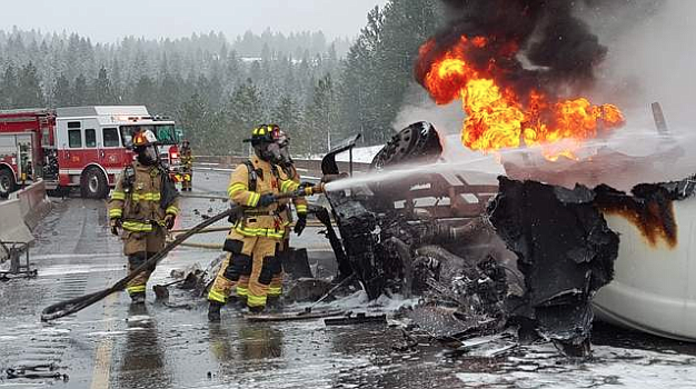 Photo by JOE WEIHERT
Firefighters with Coeur d&#146;Alene and Kootenai County Fire and Rescue attempt to put out the buring semi-truck on Interstate 90.