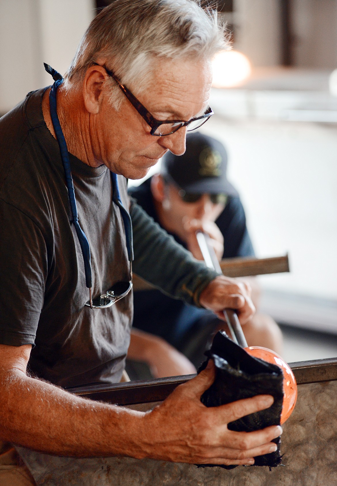 Lee Proctor shapes glass into a poppy flower as team member Brian Moore blows the glass in Bigfork.
(Brenda Ahearn file photo/Daily Inter Lake)