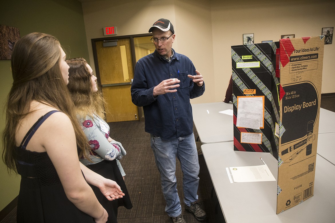 Kevin Zirker, of Post Falls, asks Post Falls High School students Lily Emerson, far left, and Julia Moore questions about their project detailing phosphoric acid in soda pop. Friday evening at the North Idaho Science and Engineering Fair. (LOREN BENOIT/Press)