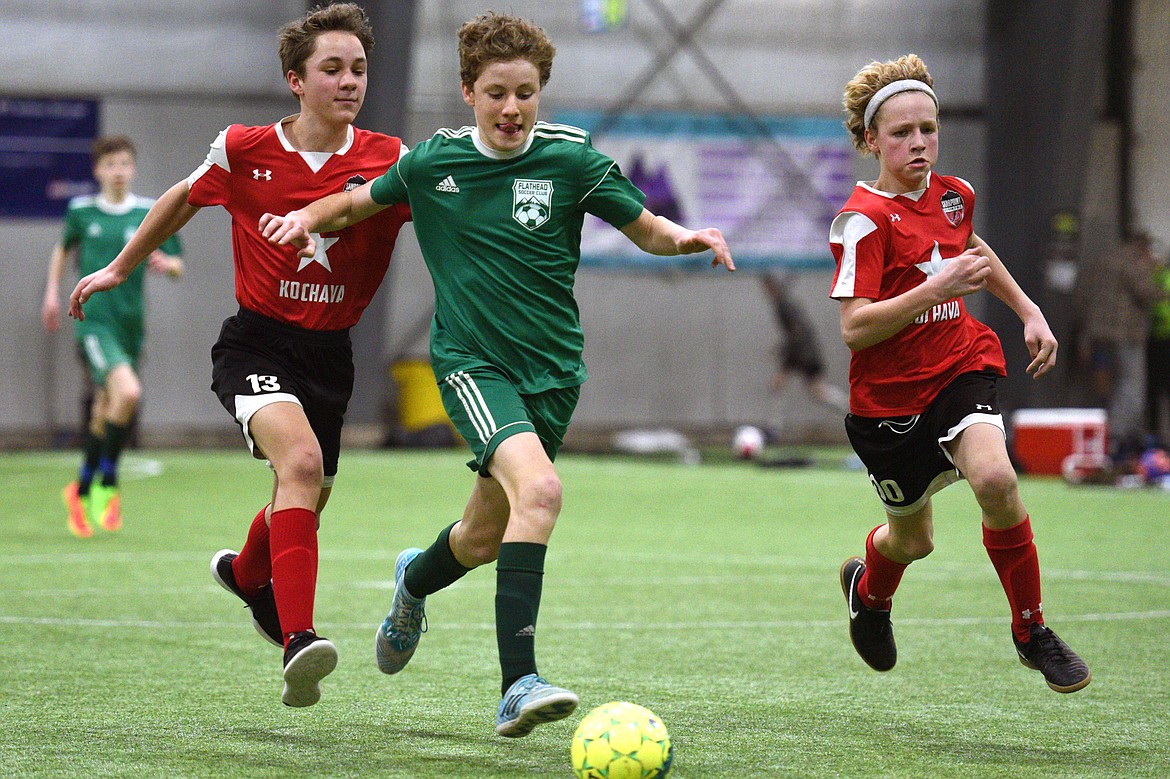 Flathead Force 03's Sullivan Coggins dribbles upfield under pressure from Sandpoint Striker defenders during the Montana Indoor Soccer Championships at the Flathead County Fairgrounds on Saturday. (Casey Kreider/Daily Inter Lake)