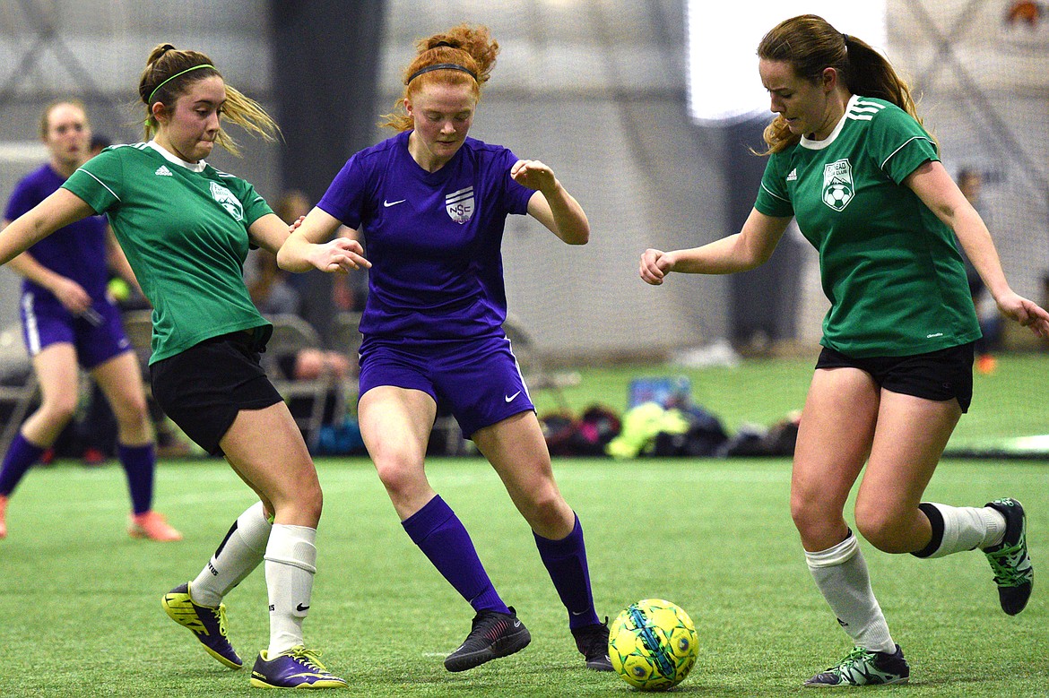 NSC Purple 00's Skyleigh Thompson dribbles between FVU Flathead Force defenders Gabby Dixon, left, and Jascah Vann during the Montana Indoor Soccer Championships at the Flathead County Fairgrounds on Saturday. (Casey Kreider/Daily Inter Lake)