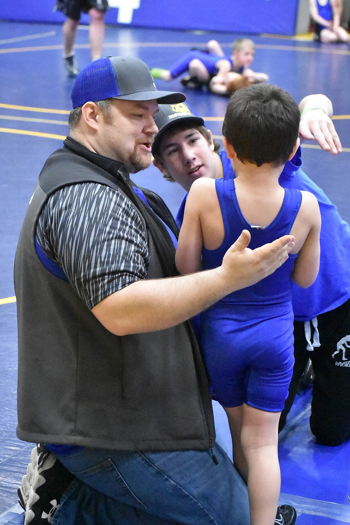 Coach Brian Barnes and referee Tucker Masters talk with Orion Roberts after a match, during the Kootenai Klassic, March 3.