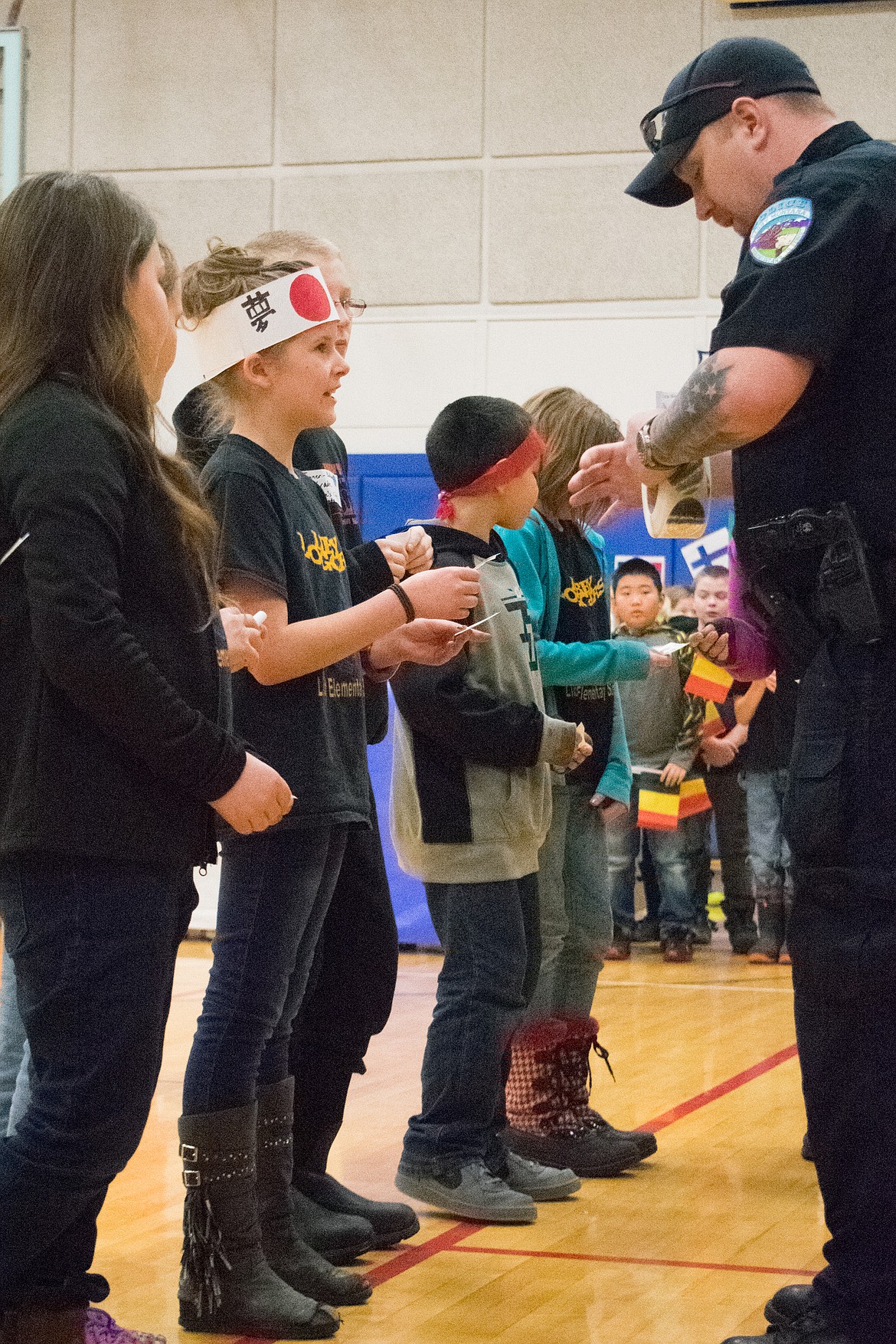 Libby police officer Chris Pape talks with Libby Elementary essay contest winner Emily Harmon. Pape handed out stickers to essay winners and participants during morning assembly at Libby Elementary School on March 2. (Ben Kibbey/The Western News)