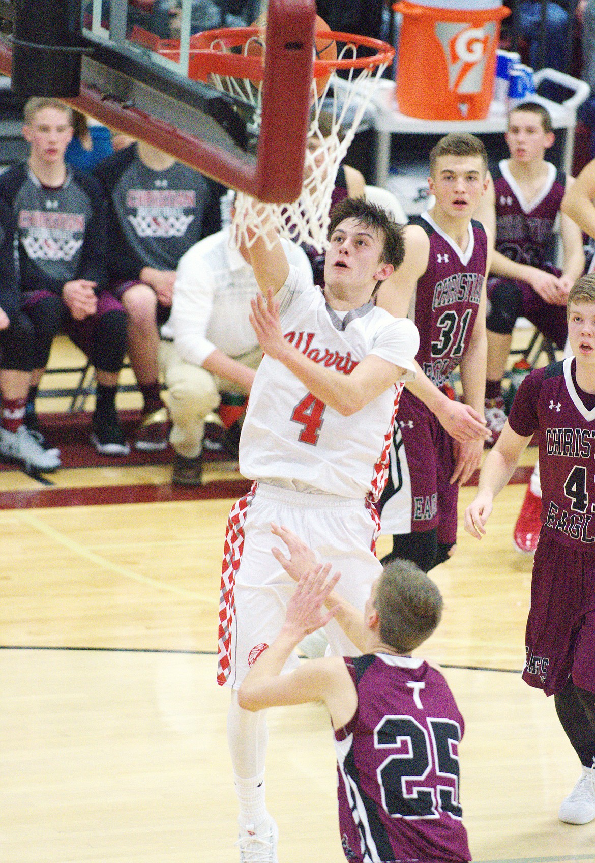 ARLEE GUARD Phillip Malatare (4) towers over Manhattan Christian defender David Aamot (23) in the first half of the MHSA Class C Western semifinal Friday night at Hamilton High School. The 69-60 victory was one of the currently undefeated Warriors perfect season. (Jason Blasco/Lake County Leader)