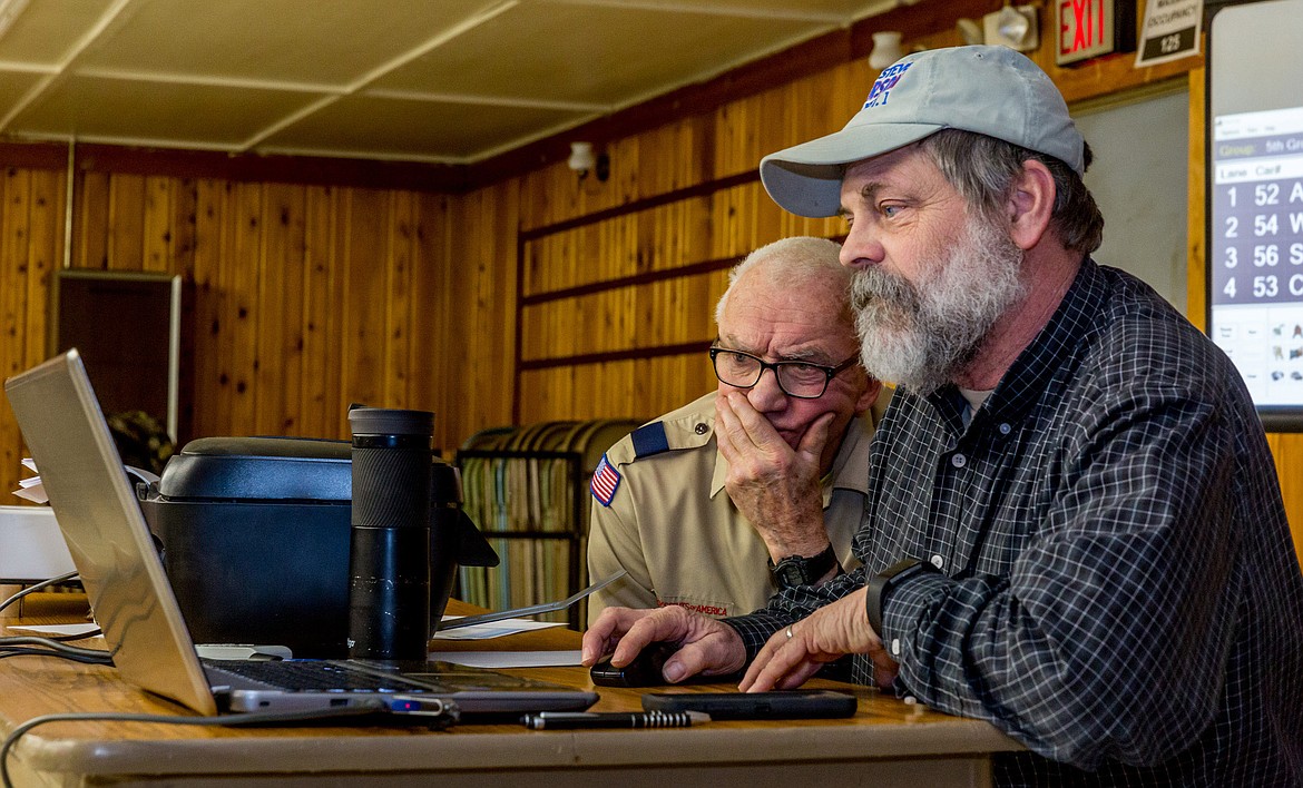 Scoutmaster Lou Kuennen, left, and Steve Gunderson sit at the pinewood derby scoring table Friday, March 2, 2018. (John Blodgett/The Western News)