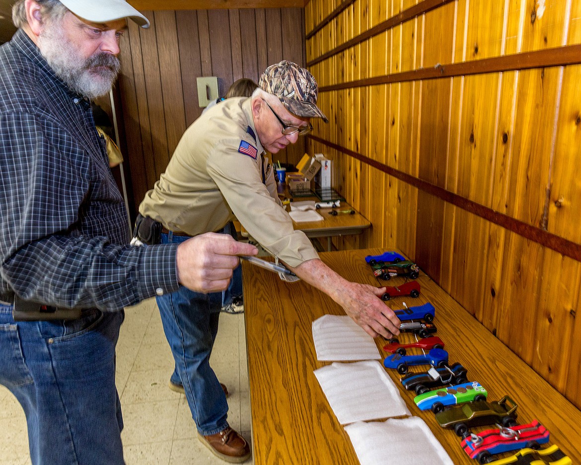 Steve Gunderson and Lou Kuennen count and inspect race cars before the beginning of the pinewood derby Friday, March 2, 2018. (John Blodgett/The Western News)