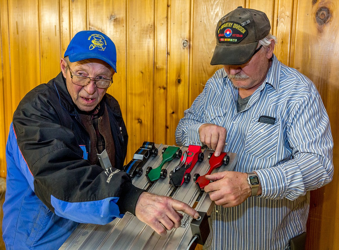 Bill Moeller, left, resets the track timer as Bernie Bosch carefully positions cars for the next race Friday, March 2, 2018. (John Blodgett/The Western News)