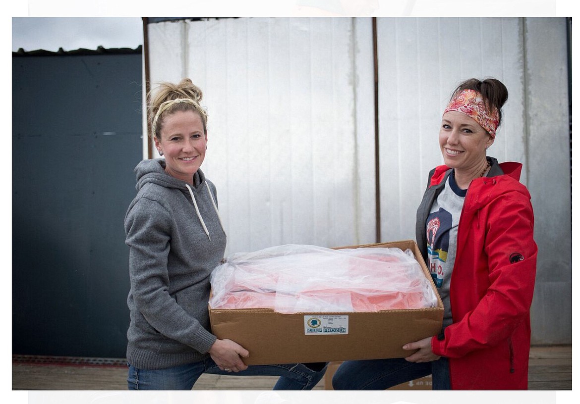 Kvichak Fish Co. owners Amanda Wlaysewski, left, and her sister Alena Chacon, hold a box of salmon fillets at their processing plant in Bristol Bay, Alaska. (Photo courtesy of Amanda Wlaysewski)