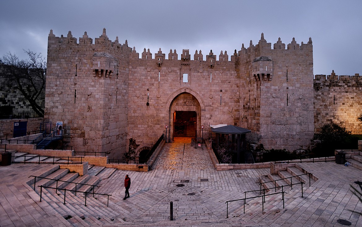 A lone commuter walks out of the Damascus Gate before sunrise on February 21, in Jerusalem. The Damascus Gate is considered one of the most beautiful gates of the Old City.(Brenda Ahearn/Daily Inter Lake)