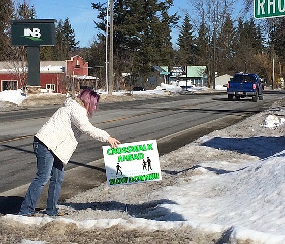 Afton Henderson places a pedestrian safety sign along Highway 41 in Spirit Lake last week. (Courtesy photo)