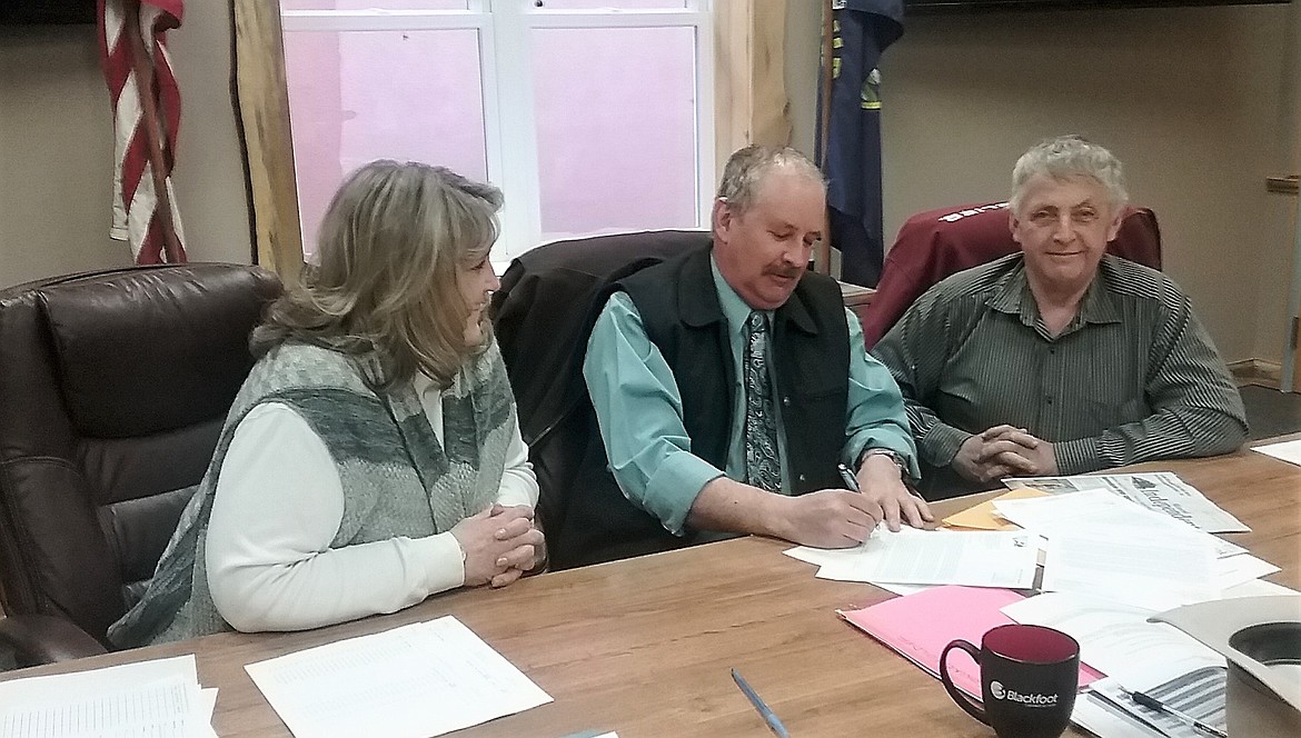 Mineral County Commissioners, Laurie Johnston (left), Roman Zylawy (middle), and Duane Simons (right) sign a letter which will be sent to the Secretary of Agriculture along with a property tax bill for U.S Forest Service land. With the loss of funding, the county has no other alternative than to assess the $445,337 tax. (Photo by Denley Loge)