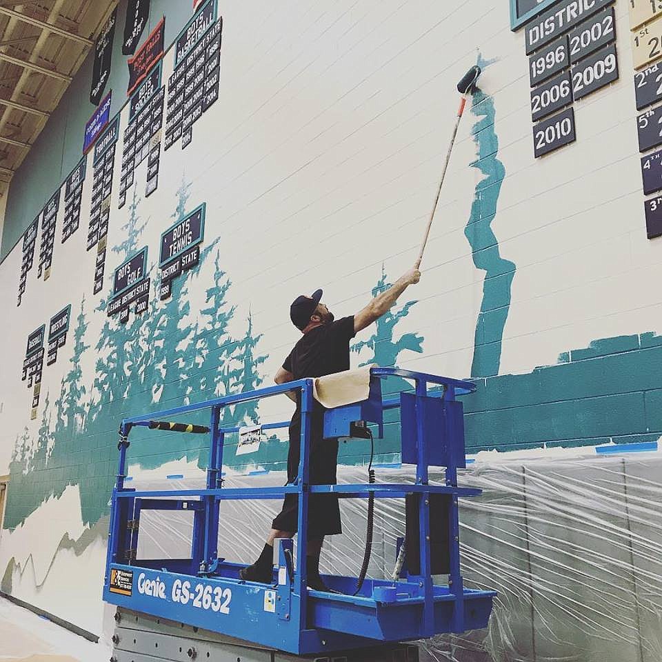 An ArtCoLab artist paints a mural on the wall of the gym at Lake City High School in Coeur d&#146;Alene. (Courtesy photos)