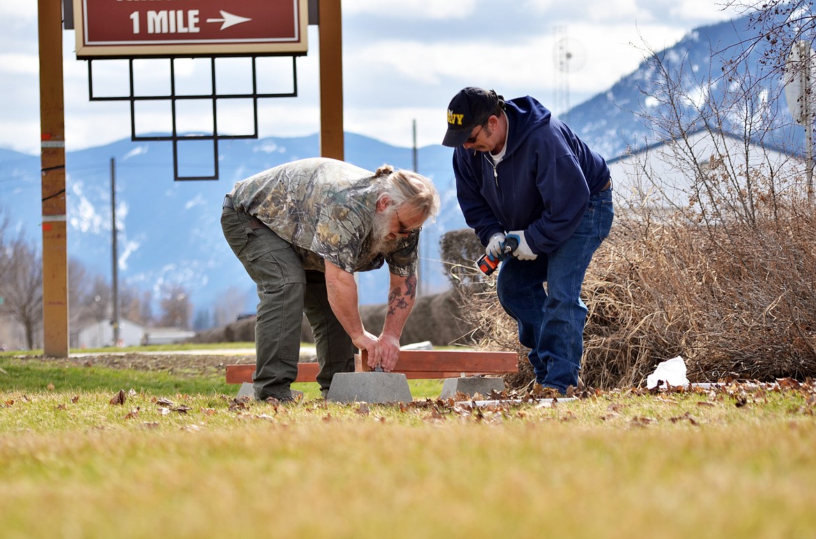David Williams, left, and Ed Foste create a display and erect flags before a small ceremony on Monday.