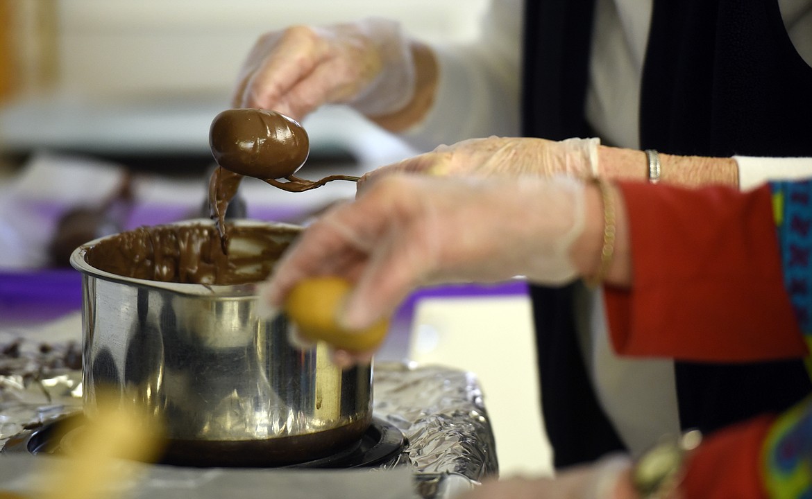 Lois Dawson dips peanut butter eggs into a mixture of milk and dark chocolate with Carol White, right, helping. The two are volunteers with the Central Christian Church which has been making the handmade Easter eggs for decades.(Brenda Ahearn/Daily Inter Lake)