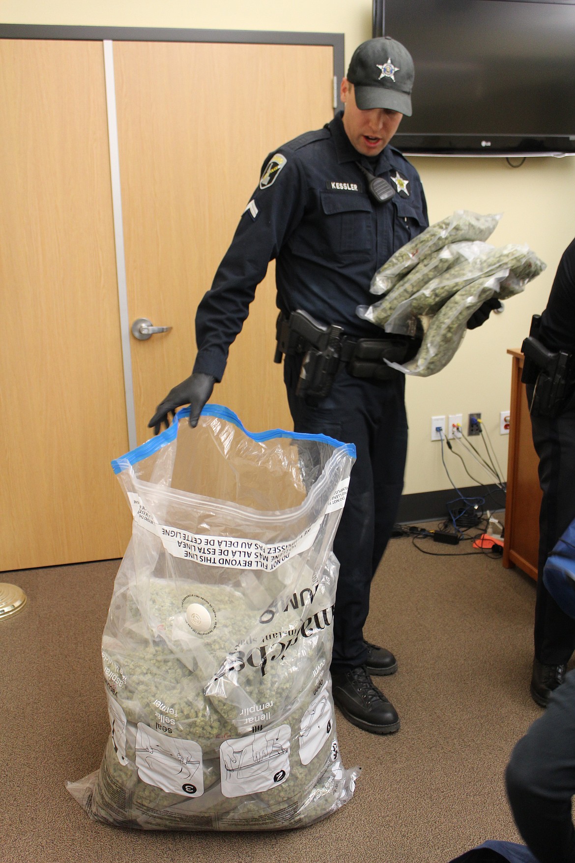 Cpl. Kevin Kessler removes storage bags of marijuana from a much larger bag to stack them. Kessler and his drug detection K9, Ace, are residents of the Silver Valley and have been instrumental in several trafficking busts over the years.