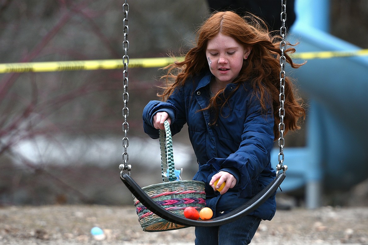 A young girl finds eggs on a swing at the 6th annual Flathead Shelter Friends Easter Egg Hunt at Woodland Park on Saturday in Kalispell. (Casey Kreider/Daily Inter Lake)