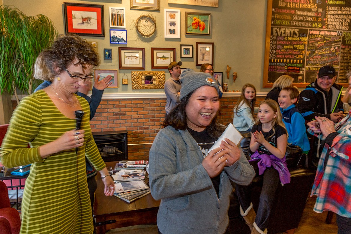 Girlie Piment, center, clutches an envelope full of donations handed to her by Kristin Smith, left, co-owner of Cabinet Mountain Brewing Company in Libby, on March 22. (John Blodgett/The Western News)