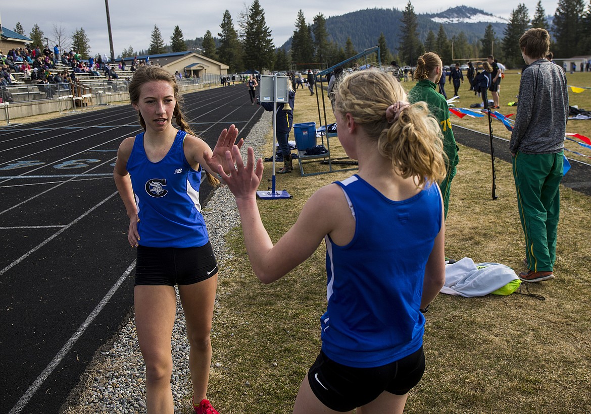 Coeur d&#146;Alene&#146;s Lu Forster, right, gives fellow Viking runner Brooklyn Shell a high-five for crossing first in the 1,600-meter run Friday evening at the Kootenai County Challenge.