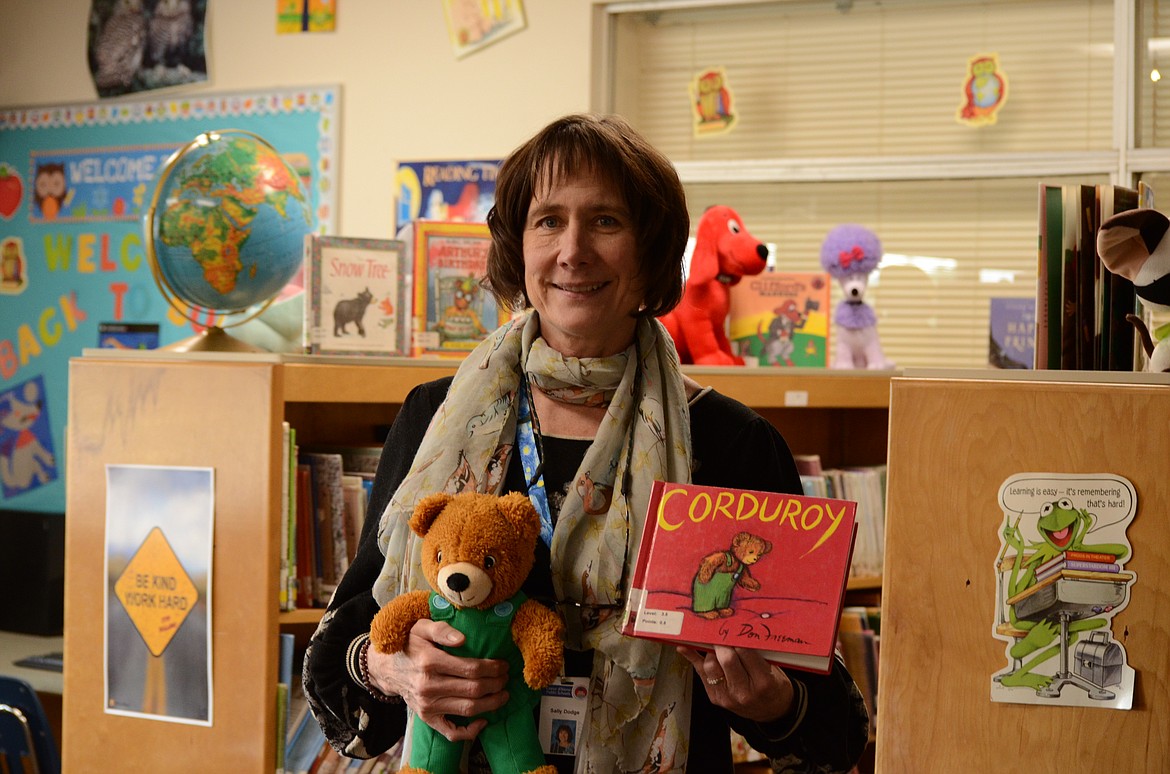 Sally Dodge stands with her favorite book and matching stuffed animal at the Borah Elementary Library.