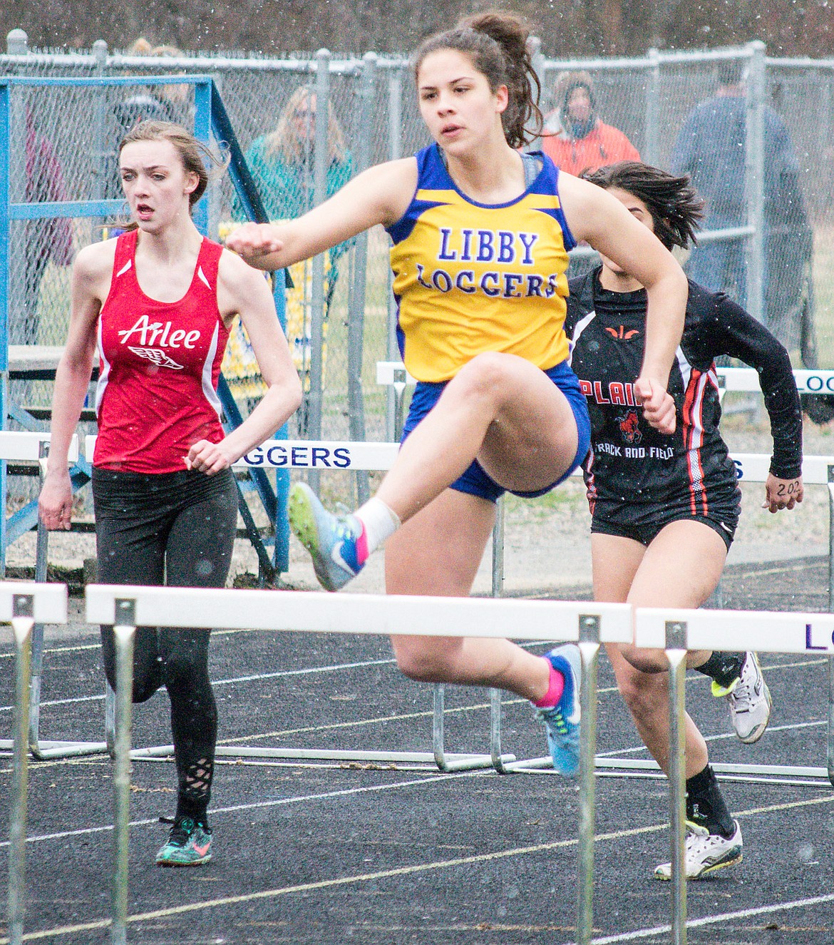 With snow falling all around, Libby junior Bella Hollingsworth runs to second place in the 100m hurdles at the Eureka Invitational hosted at Libby High School, April 7. (Ben Kibbey/The Western News)