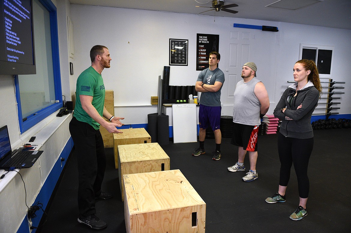 Bigfork Crossfit owner Isaac Lee speaks to, from left, Brant Beaudry, Cole Armstrong and Nikkie Armstrong at the start of a class on Wednesday, March 28. (Casey Kreider/Daily Inter Lake)