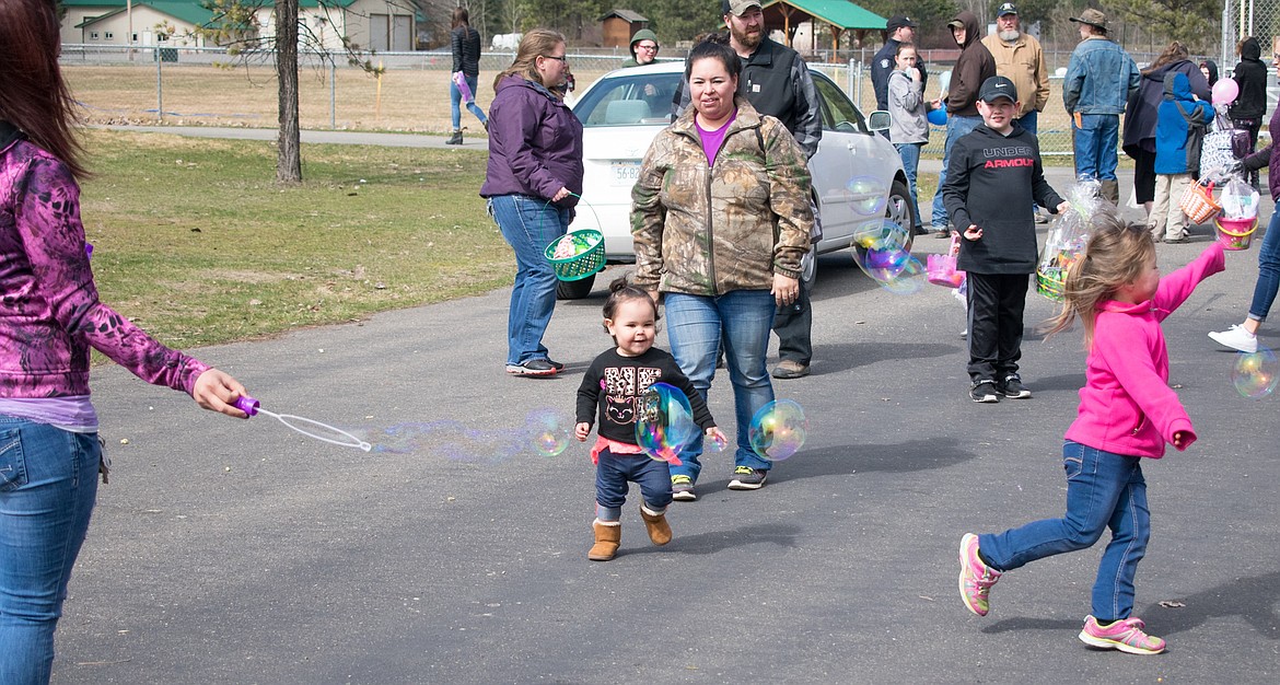 Katelynn Cratty (center) chases bubbles her mother, Ashley, is blowing, along with Hailee Lampton (right) while her mother, Terri, looks on at the Easter egg hunt at Roosevelt Park in Troy, March 31. (Ben Kibbey/The Western News)