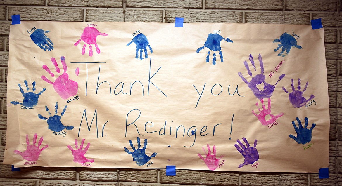 Redinger proudly displays a handmade thank you with the painted handprints of students who received some of his toys in his home workshop. &#160;(Brenda Ahearn/Daily Inter Lake)