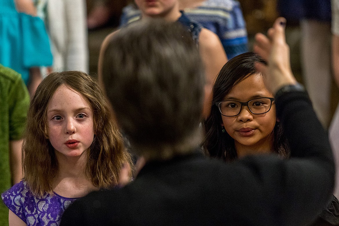 Matilda Newton, left, and Aritchmae Pineda follow Choir Director Lorraine Braun&#146;s direction during a dinner and auction benefitting the Libby Children&#146;s Select Choir Friday evening at Libby Elementary School. (John Blodgett/The Western News)
