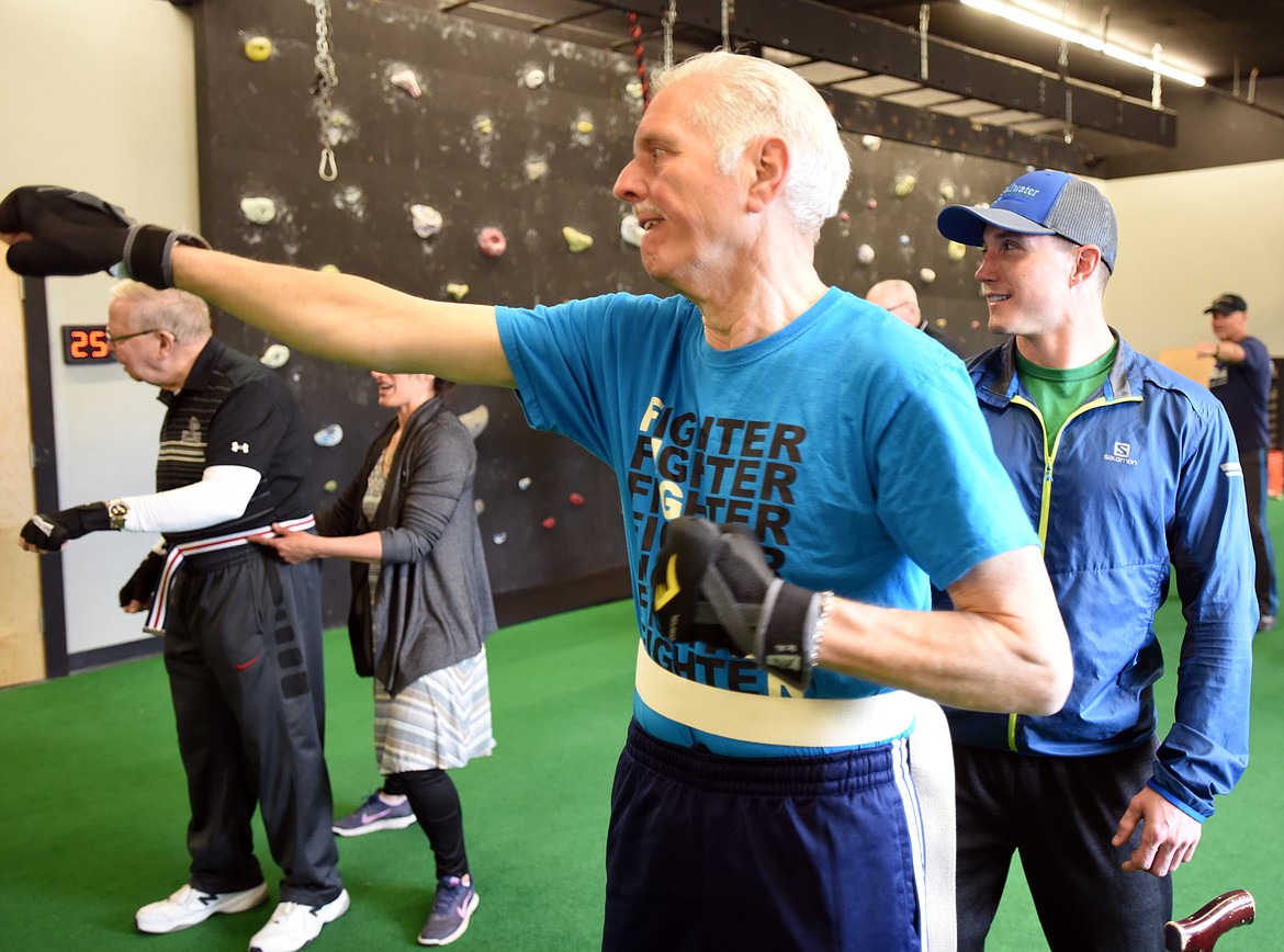 Tom Mohler doing shadowboxing drills as volunteer Ryan Ross keeps a close watch to help him stay stable during the RockSteady Boxing for Parkinson&#146;s class on Wednesday morning, April 25, at Access Fitness in Kalispell. In the background Norm Hagen and volunteer Loretta Merriman work on the same drills.
(Brenda Ahearn/Daily Inter Lake)