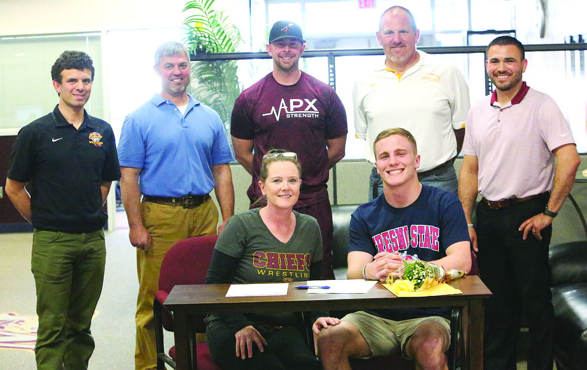 Connor Vanderweyst/Columbia Basin Herald
Moses Lake wrestler Hunter Cruz (sitting) poses for a picture after signing a national letter of intent to compete for Fresno State University.