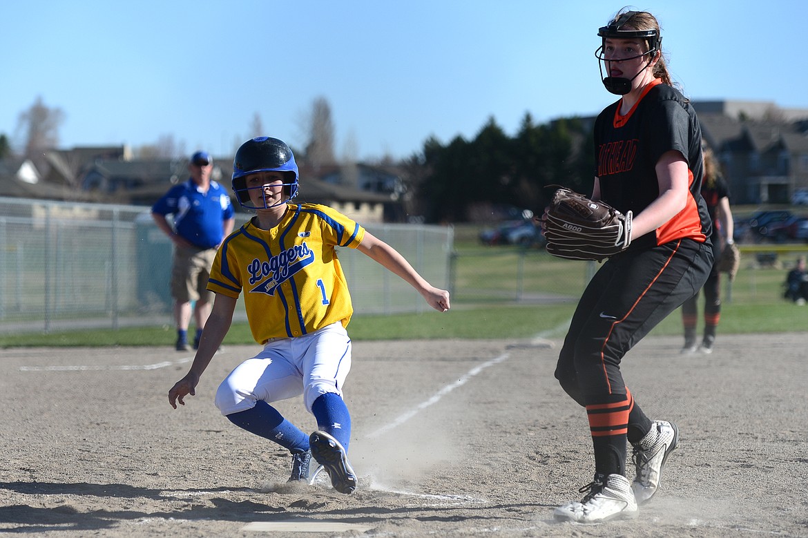 Libby's Ashlyn Monigold scores on a wild pitch in front of Flathead pitcher Karissa Comer on Tuesday. (Casey Kreider/Daily Inter Lake)