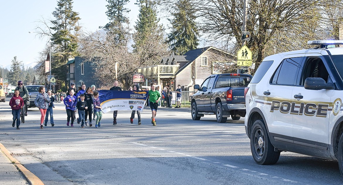 Escorted by Troy Police, students from from WF Morrison Elementary School in Troy carried the annual Law Enforcement Torch Run for Special Olympics banner through town and accompanied the Special Olympics Torch down Highway 2 to Trojan Lanes on Wednesday. (Ben Kibbey/The Western News)