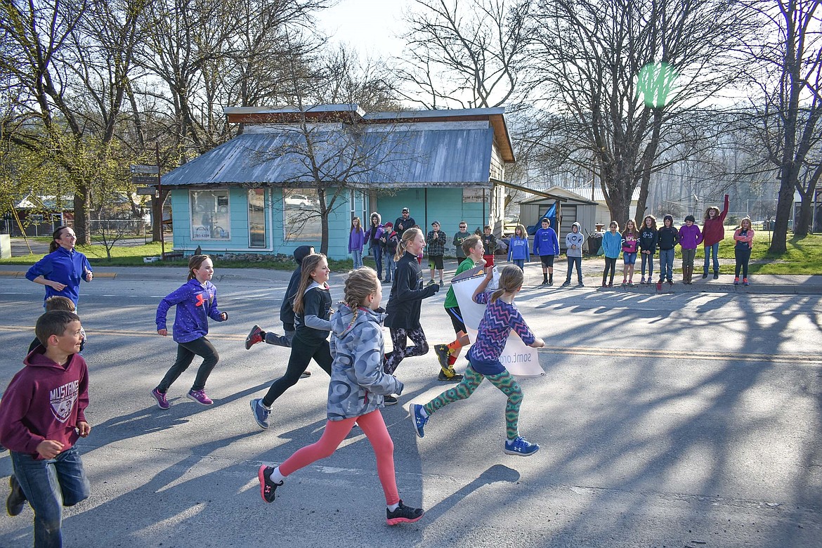 Cheered on by classmates, students from from WF Morrison Elementary School in Troy carried the annual Law Enforcement Torch Run for Special Olympics banner through Troy, accompanying the Special Olympics Torch down Highway 2 to Trojan Lanes on Wednesday. (Ben Kibbey/The Western News)