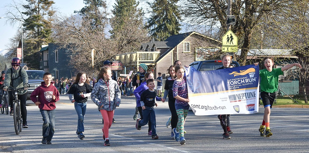 Escorted by Troy Police and cheered on by classmates lining the roadway, students from from WF Morrison Elementary School in Troy carried the annual Law Enforcement Torch Run for Special Olympics banner through town and accompanied the Special Olympics Torch down Highway 2 to Trojan Lanes on Wednesday. (Ben Kibbey/The Western News)