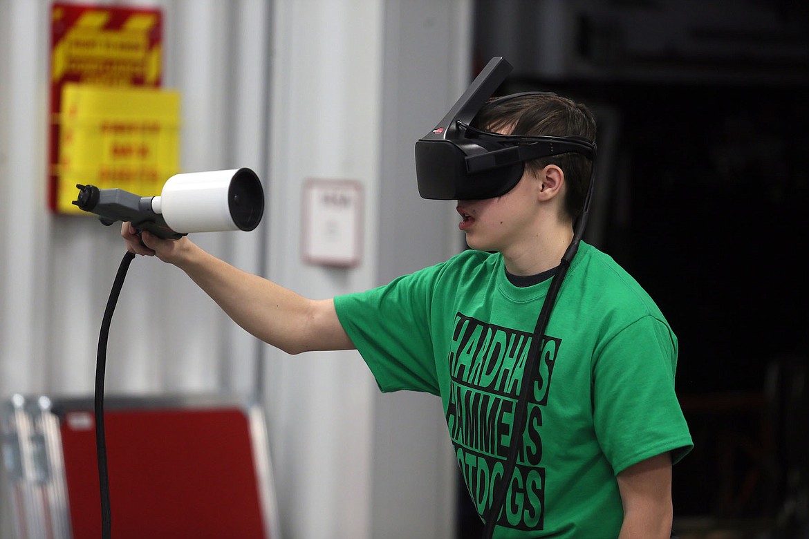 Post Falls High School sophomore Patrick Moore painted a car door with the help of a virtual reality trainer at the 10th annual Hard Hats, Hammers &amp; Hot Dogs event Friday. (JUDD WILSON/Press)