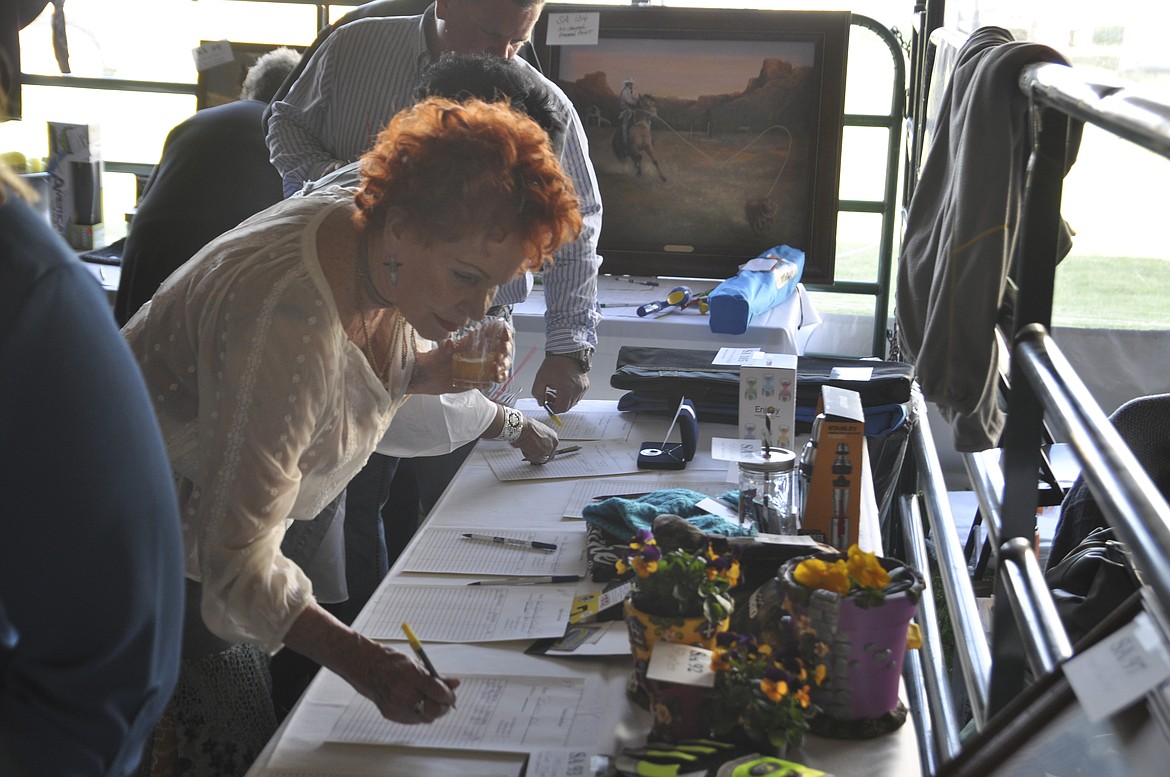 JOAN PLATKO of Polson makes an entry for a silent auction at the Cowboy Ball. (Ashley Fox/Lake County Leader)