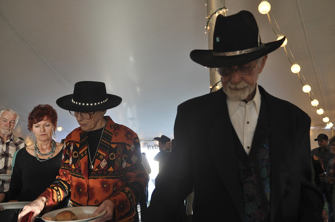 BARBARA STONE, center, and husband Russell, right, get some dinner at the Cowboy Ball in Polson. The couple has attended the fundraiser every year of its existance, for 28 years. (Ashley Fox/Lake County Leader)