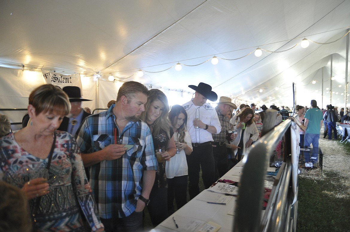 AS THEY enjoyed the spring evening, community members gaze at the live and silent auction items at the 28th Cowboy Ball at the Polson Fairgrounds. (Ashley Fox/Lake County Leader)