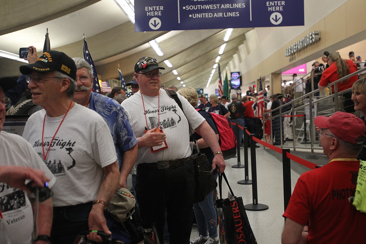 Air Force and Vietnam veteran Russell Thomas, 72, of Coeur d'Alene, smiles back at one of many friends in the crowd Tuesday night as he makes his way through the welcome line in the Spokane International Airport. Thomas was one of nearly 100 regional veterans who left for Washington, D.C. Monday morning to embark on a quick but significant journey to see America's military memorials. (DEVIN WEEKS/Press)