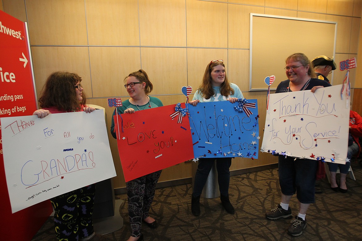 Loved ones of Honor Flight veteran Russell Thomas of Coeur d'Alene hold up signs they made for their much-loved dad and grandpa. From left: Emma Leuck, 13, Maggie Moore, 18, Sierra Leuck, 18, and Margaret Leuck, all of Coeur d'Alene. (DEVIN WEEKS/Press)
