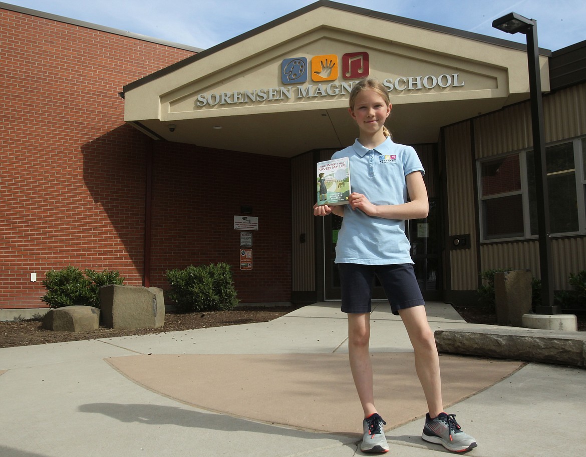 DEVIN WEEKS/Press
Sorensen Magnet School of the Arts and Humanities fifth-grader Emmaline Spyra holds up the book &#147;The War That Saved Me&#148; while standing in front of her school Thursday. Emmaline raised nearly $400 she donated to the Shriners Children&#146;s Hospital in Spokane to help pay for corrective treatment for kids with clubfeet. She was inspired to help because of the book, which is about a girl with a clubfoot who lives in sad isolation.