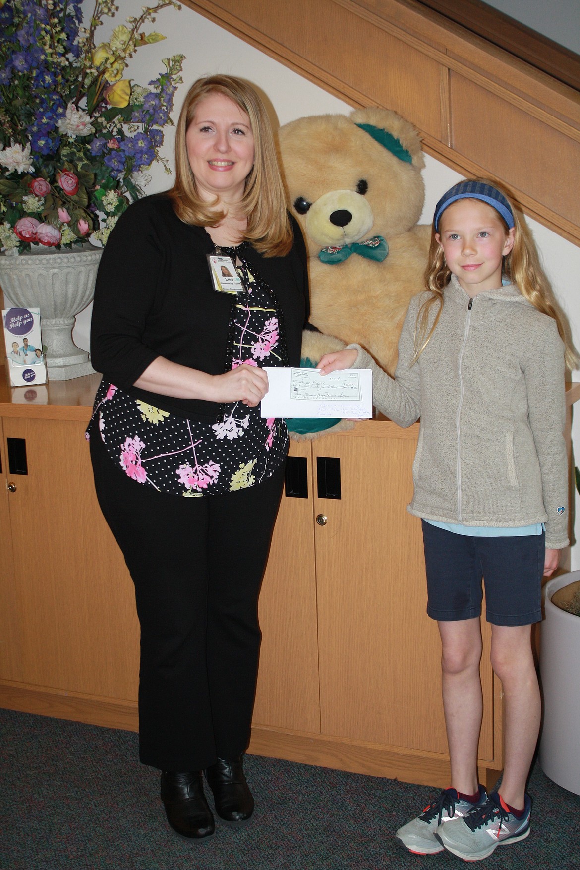 Shriners Children's Hospital &#151; Spokane physical therapist Barb Harrison receives a check for nearly $400 from Sorensen fifth-grader Emmaline Spyra early Thursday morning. Emmaline was inspired to donate to the hospital to help kids with clubfeet after reading about the condition in a historical fiction novel and seeing a homeless man with clubfeet while on a family trip. (Courtesy photo)