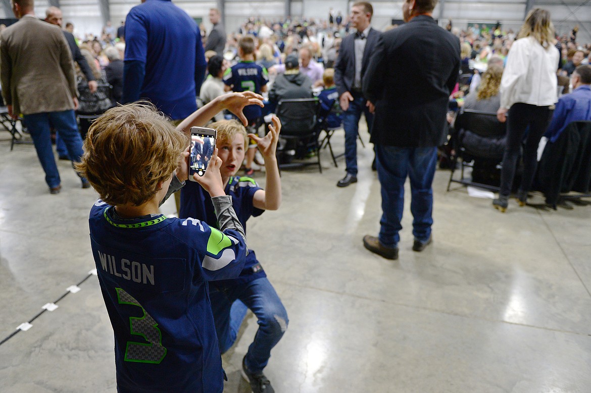 Fans of Seattle Seahawks quarterback Russell Wilson take photos in front of his table at an event held by Stillwater Christian School at the Flathead County Fairgrounds in Kalispell on Wednesday. (Casey Kreider/Daily Inter Lake)