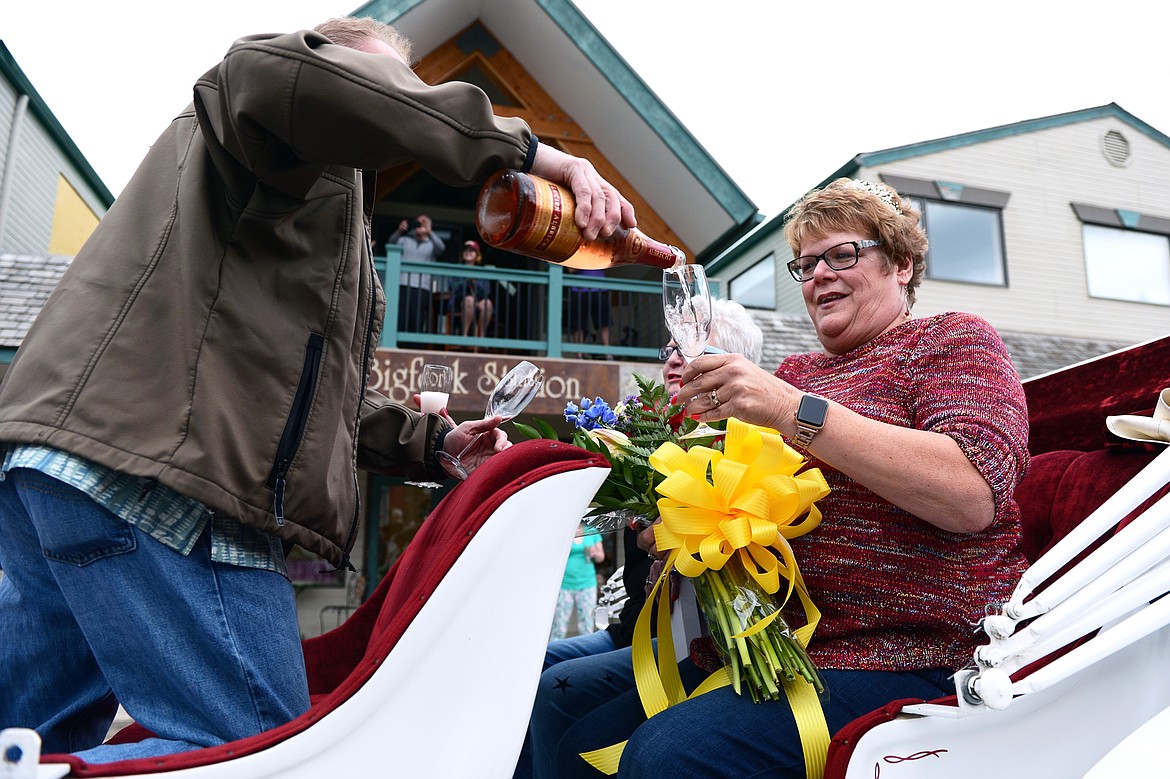 Donna Lawrence is poured a glass of wine as she rides in the back of a horse-drawn carriage during a surprise parade Saturday evening in honor of her retiring from The Jug Tree in downtown Bigfork.