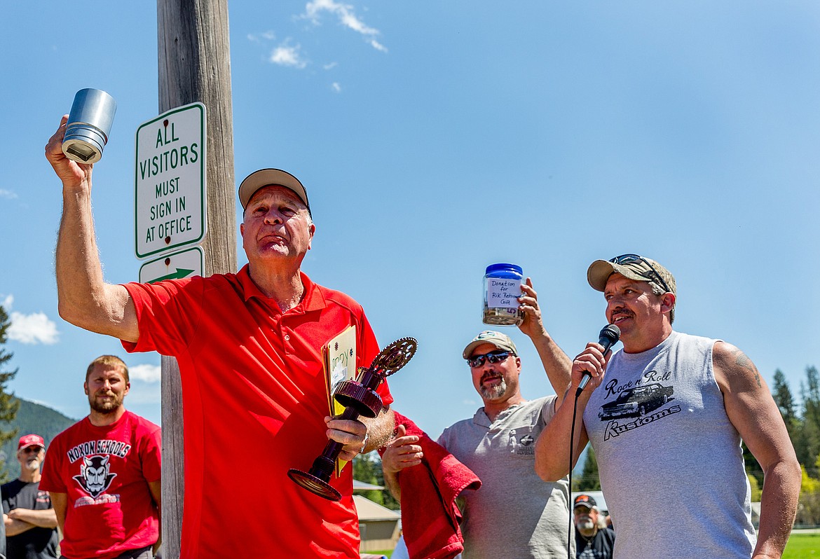 Rik Rewerts holds a mug and trophy presented to him by Igniters Car Club member Darren Short, right, at a surprise retirement party held at the end of a car show at Noxon High School Friday. Rewerts, who was principal at Libby High School for 20 years before retiring in 2013, is retiring for good after five years as Noxon High School principal. (John Blodgett/The Western News)