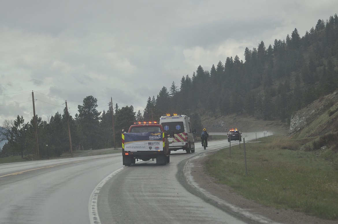 POLSON POLICE lead the way for Forrest Neimyer, who rides his bicycle through scattered rain showers from Rollins to Elmo Monday afternoon for the Special Olympics of Montana. (Ashley Fox/Lake County Leader)