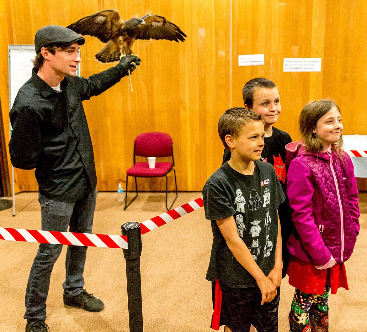 Keaton Buell, left, poses Skybird, a Swainson&#146;s hawk, as backdrop for a photo of Blaise Erickson, foreground, Joe Thompson and Makayla Thompson after a presentation at Libby Dam Saturday, April 28, 2018. (John Blodgett/The Western News)