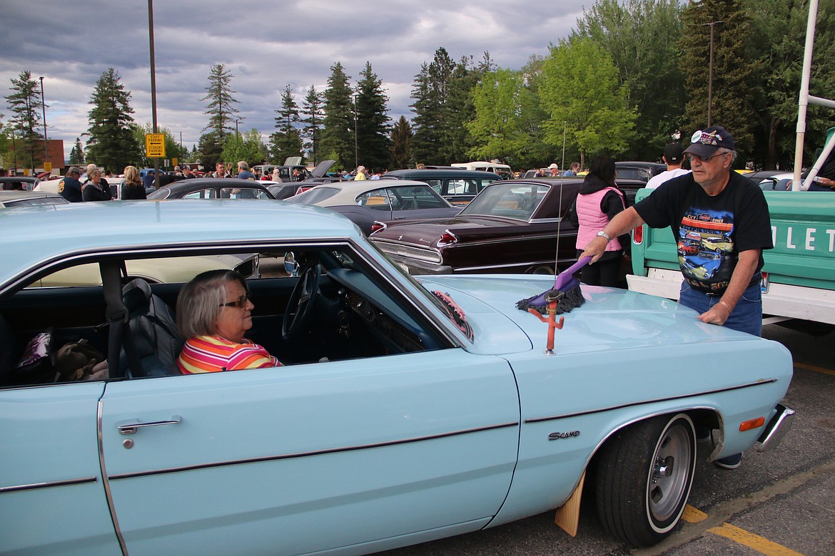 (Photo by MARY MALONE)A classic car owner brushes his car off at Sandpoint High School as he waits for the start of the Lost in the '50s car parade on Friday night.