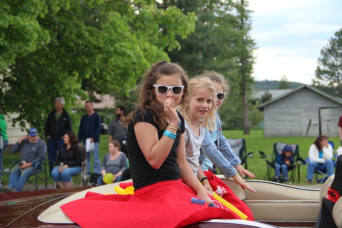 A trio sit in the back of a classic car as it makes its way through Sandpoint during a past Lost in the '50s car parade.